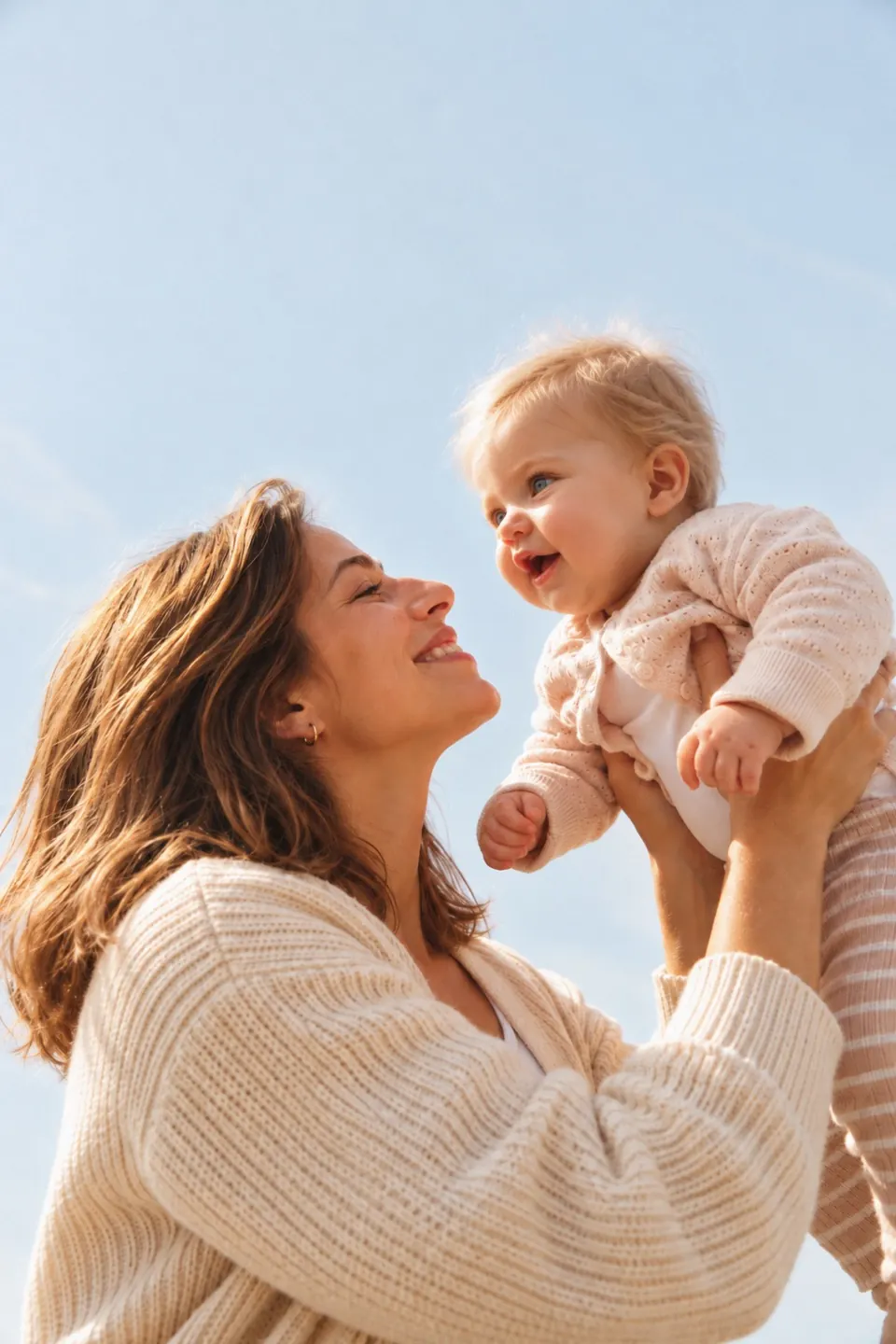 Mutter und Baby schauen sich beim Hochheben lächelnd an