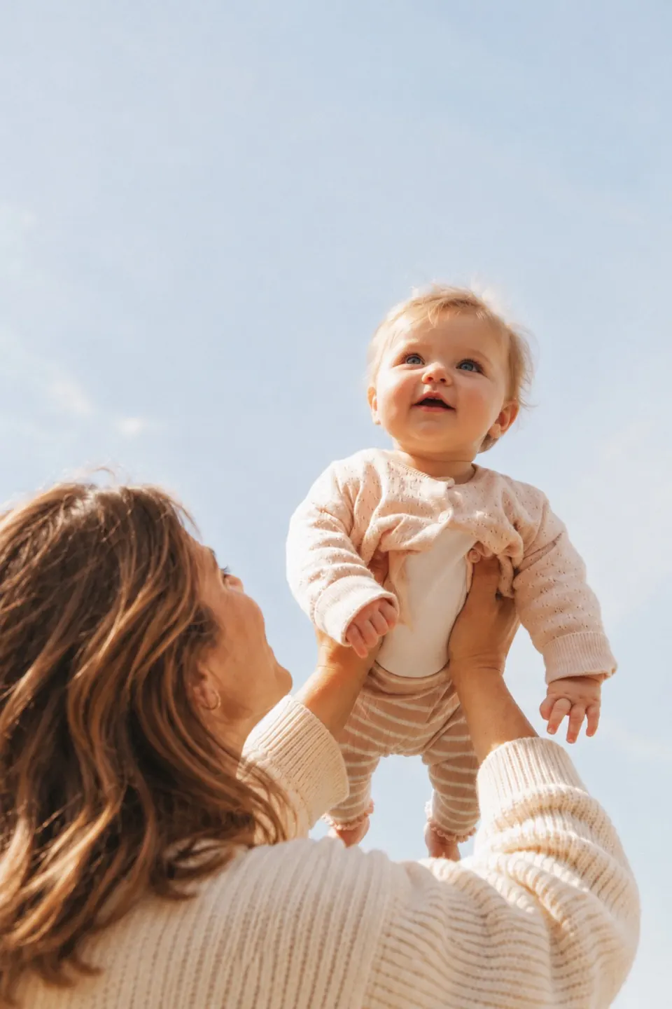 Baby wird von seiner Mutter in den hellen Himmel gehoben